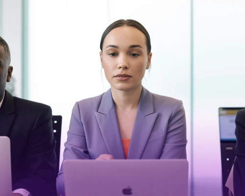 Woman in a lilac blazer working on a laptop